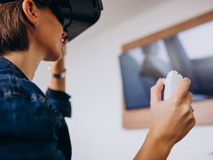 Young woman wearing vr glasses playing virtual game using remote